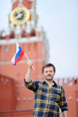 Middle age man with russian flag with Spasskaya tower (Russia, Moscow) on background clipart