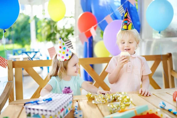 Küçük bir çocuk ve eğlenceli ve doğum günü parti renkli dekorasyon ve kek kutlamak olan kız — Stok fotoğraf