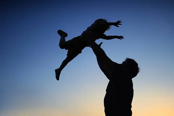 父と一緒に屋外ファンを持つ彼の幼い息子を愛する。夕日にシルエットとしての家族. — ストック写真