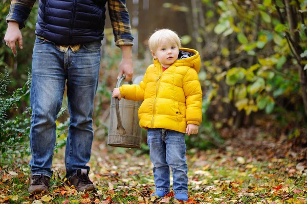 Netter Junge hilft seinem Vater Pflanzen im Garten zu gießen — Stockfoto