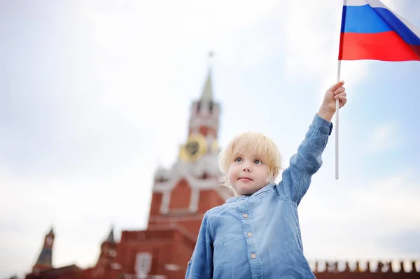 Милый мальчик с российским флагом с Спасской башней Россия, Москва на заднем плане — стоковое фото