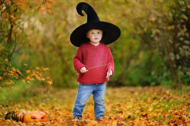 Sivri şapkalı açık havada sihirli değnek ile oynarken yürümeye başlayan çocuk