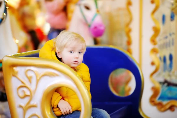 Liten unge ridning på färgglada carousel (merry go round) under marknaden — Stockfoto