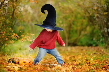 Sivri şapkalı açık havada sihirli değnek ile oynarken yürümeye başlayan çocuk