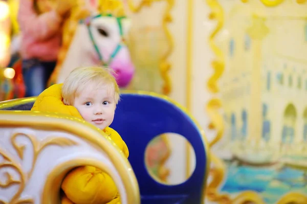 Little kid riding on colorful carousel (merry go round) — Stock Photo, Image