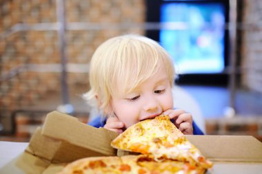 Sevimli sarışın çocuk dilim pizza fast food restoranında yemek