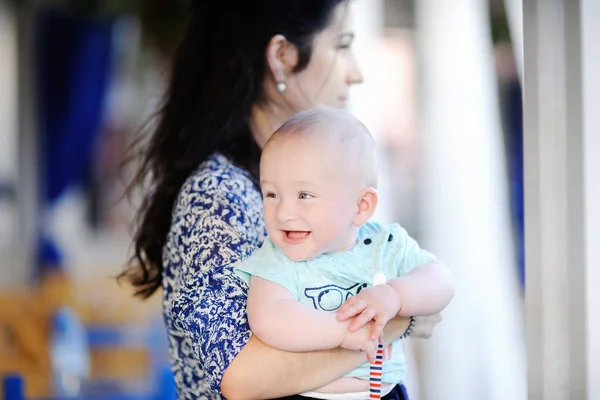 Junge Mutter hält ihren lächelnden kleinen Jungen — Stockfoto