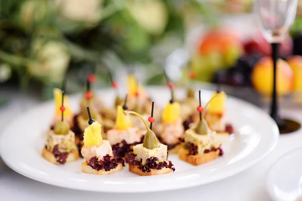 Deliciosos bocadillos de canapé con topping de piña y alcaparras servidos en una fiesta o recepción de boda —  Fotos de Stock