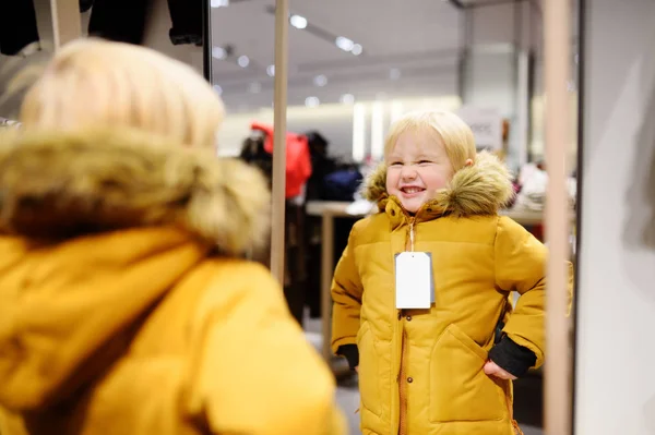 Bonito menino tentando casaco novo durante as compras — Fotografia de Stock