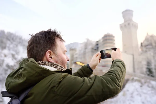 Handsome milddle age man making photo of famous royal castle Neuschwanstein — Stock Photo, Image