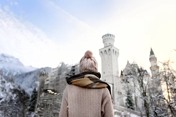 Ung kvinna tittar på berömda kungliga slottet Neuschwanstein i vinterdag — Stockfoto