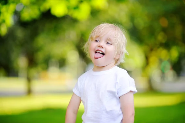 Outdoors portrait of funny emotional little boy sticking tongue out — Stock Photo, Image