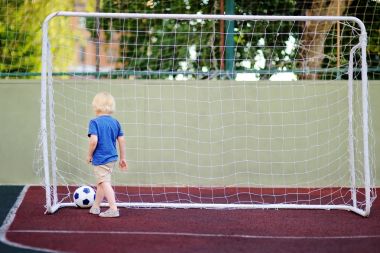 Küçük çocuk yaz gününde bir futbol/futbol oyunu oynarken eğleniyor
