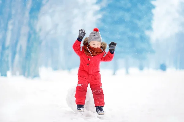 Menino em roupas vermelhas de inverno se divertindo com bola de neve — Fotografia de Stock