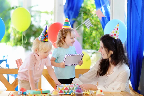 Kindje en hun moeder vieren verjaardagspartij met kleurrijke decoratie en gebak met kleurrijke decoratie en Limburgse vlaai — Stockfoto