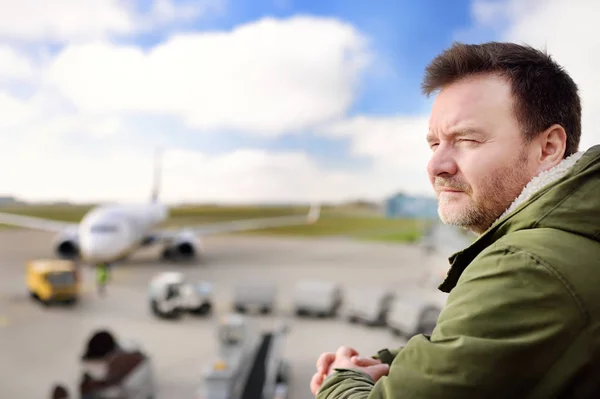 Middelbare leeftijd dude kijken vliegtuigen in internationale luchthaven — Stockfoto