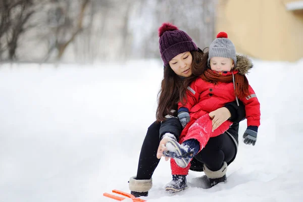 Jonge Aziatische vrouw helpen Kaukasische peuter jongen met zijn winter-kleding — Stockfoto