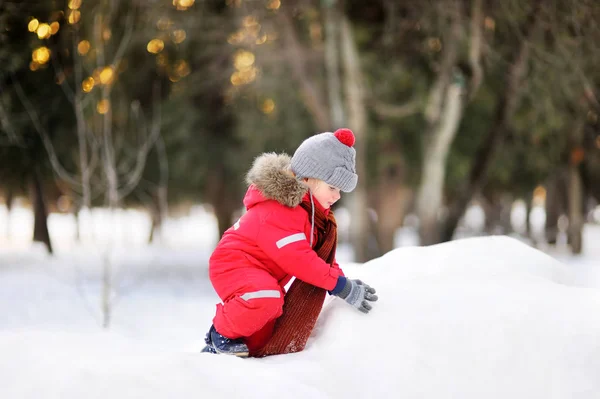 穿红色冬衣的小男孩用新鲜的雪玩 — 图库照片