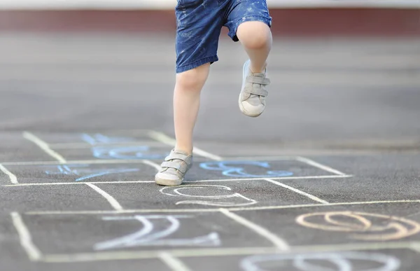 Close-up de pernas de menino e hopscotch desenhado em asfalto — Fotografia de Stock