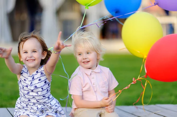 Liten pojke och flicka att ha kul och fira födelsedagsfest med färgglada ballonger — Stockfoto