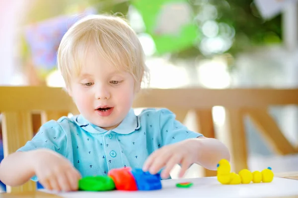 Menino criativo brincando com argila de modelagem colorida no jardim de infância — Fotografia de Stock