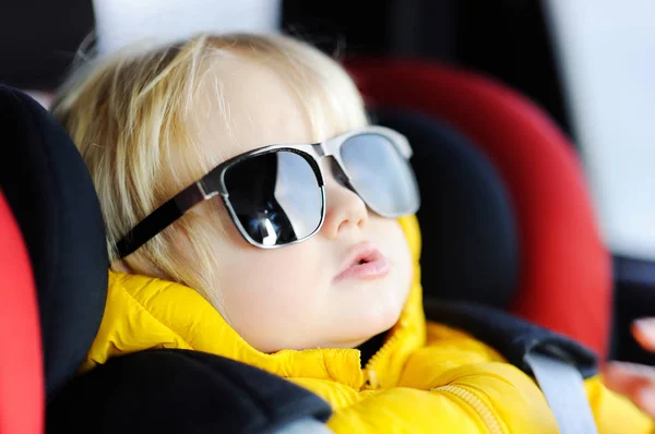 Portrait of cute funny little boy wearing father's sunglasses sitting in car seat — Stock Photo, Image