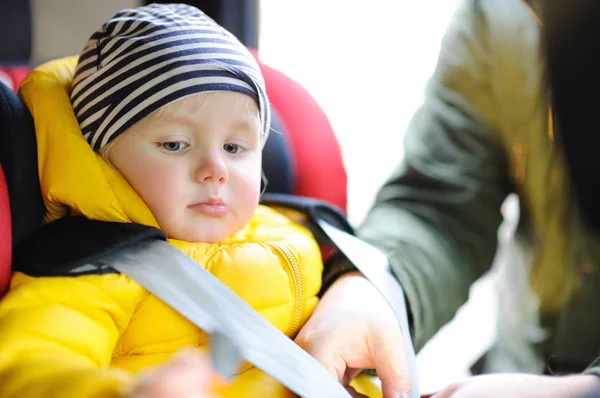 Father helps his toddler son to fasten belt on car seat — Stock Photo, Image