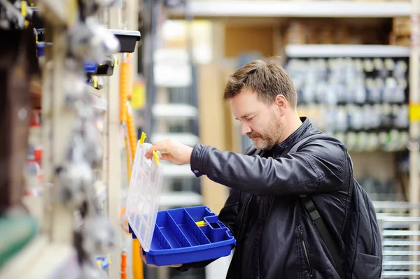 Homem de meia idade escolhendo a caixa de ferramentas certa em uma loja de ferragens — Fotografia de Stock