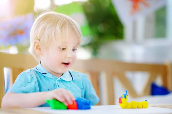 Menino criativo brincando com argila de modelagem colorida no jardim de infância — Fotografia de Stock