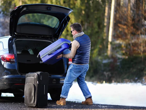 Hombre guapo yendo de vacaciones, cargando su maletero con la maleta —  Fotos de Stock