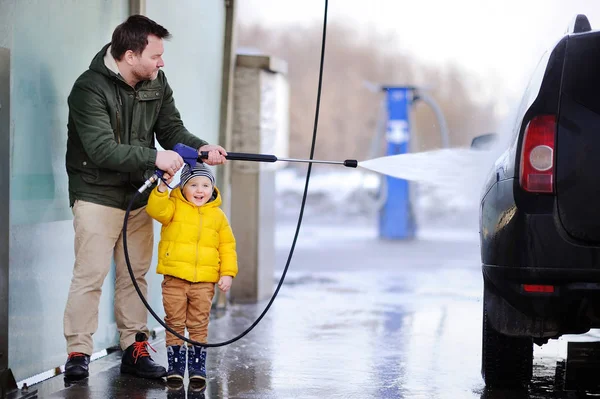 Mann mittleren Alters und sein kleiner Sohn beim Autowaschen in einer Waschanlage — Stockfoto