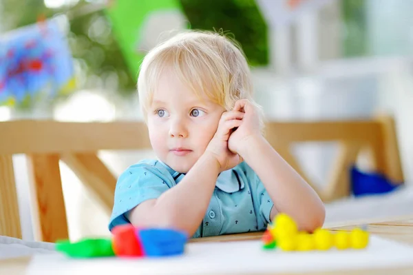 Chico creativo jugando con arcilla de modelado de colores en el jardín de infantes —  Fotos de Stock