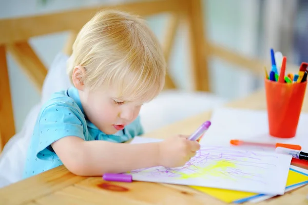 Милый мальчик рисует и рисует красочными маркерами ручки в детском саду — стоковое фото