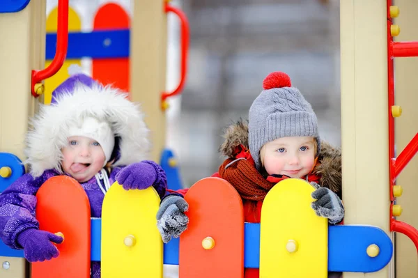 Ragazzino e ragazza in abiti invernali divertirsi all'aperto parco giochi — Foto Stock