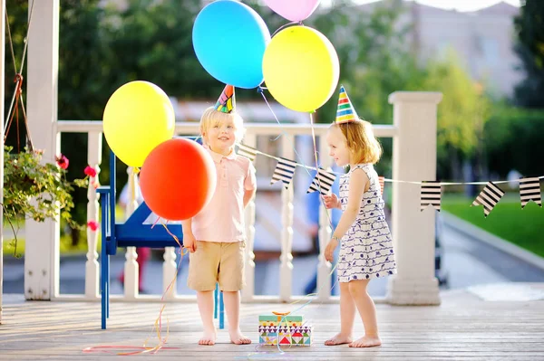 Niño y niña se divierten y celebran fiesta de cumpleaños con globos de colores — Foto de Stock