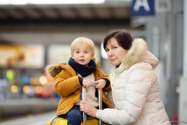 Menino bonito e sua avó / mãe esperando trem expresso na plataforma da estação ferroviária — Fotografia de Stock