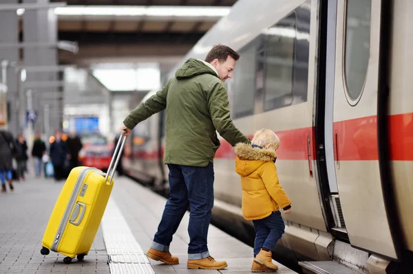 Niño y su padre van en tren expreso en la plataforma de la estación de tren —  Fotos de Stock