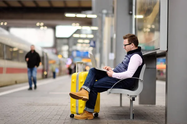 Freelancer working with a laptop in a train station while is waiting for transport — Stock Photo, Image