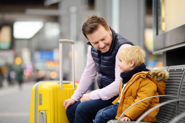Niño y su padre esperando tren expreso en la plataforma de la estación de tren o esperando su vuelo en el aeropuerto — Foto de Stock