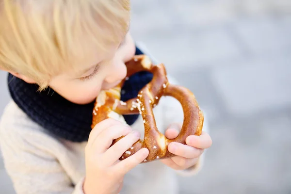 Pouco turista comer pão tradicional bávaro chamado pretzel — Fotografia de Stock