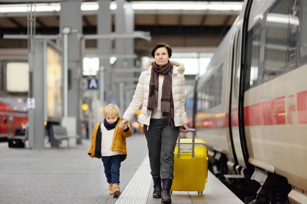 Lindo niño y su abuela / madre esperando tren expreso en la plataforma de la estación de tren — Foto de Stock