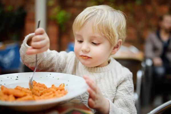 Lindo niño comiendo pasta en italiano restaurante interior —  Fotos de Stock
