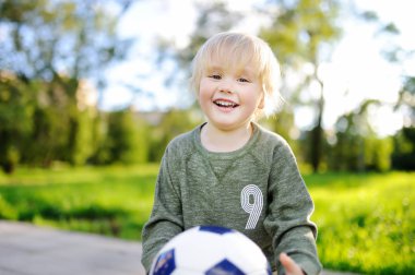 Küçük çocuk güneşli yaz gününde bir futbol oyunu oynarken eğleniyor