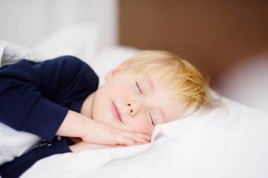 Sevimli küçük çocuk uyuyor. Yorgun çocuk ebeveynin yatakta şekerleme.