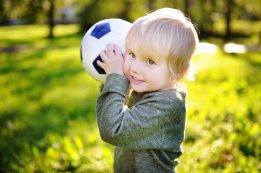 Küçük çocuk güneşli yaz gününde bir futbol oyunu oynarken eğleniyor