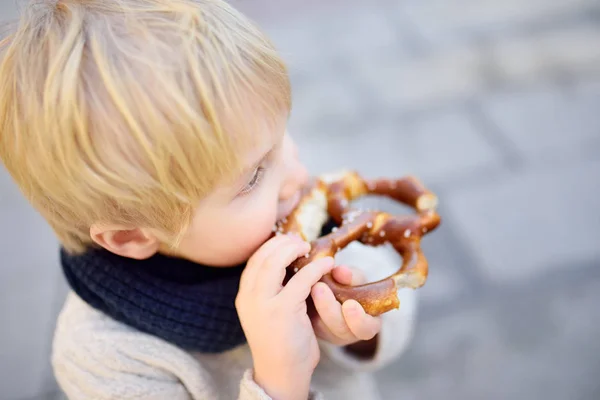 Piccolo turista mangiare pane bavarese tradizionale chiamato pretzel — Foto Stock