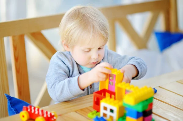 Мальчик играет с красочными пластиковыми блоками в детском саду или дома — стоковое фото