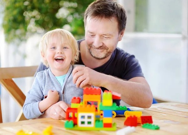 Kleiner Junge mit seinem Vater spielt zu Hause mit bunten Plastikklötzen — Stockfoto