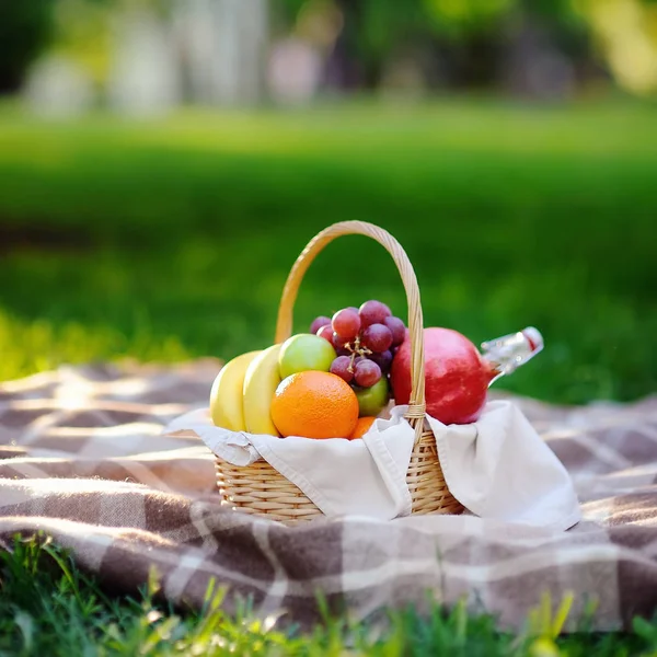 Cesta de piquenique com frutas, alimentos e água na garrafa de vidro — Fotografia de Stock