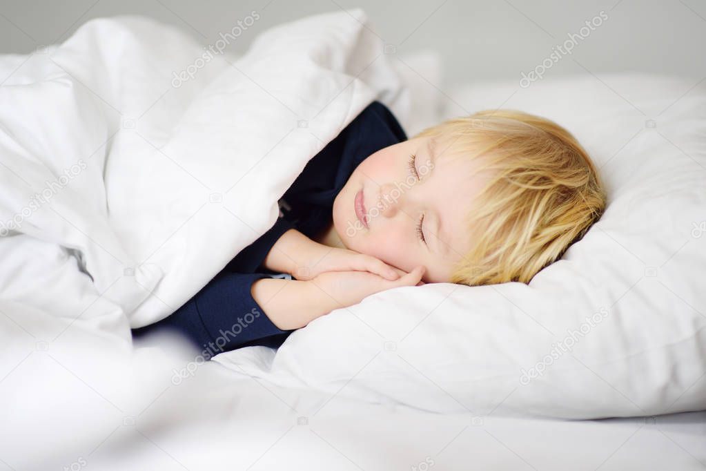 Cute little boy sleeping. Tired child taking a nap in parent's bed.